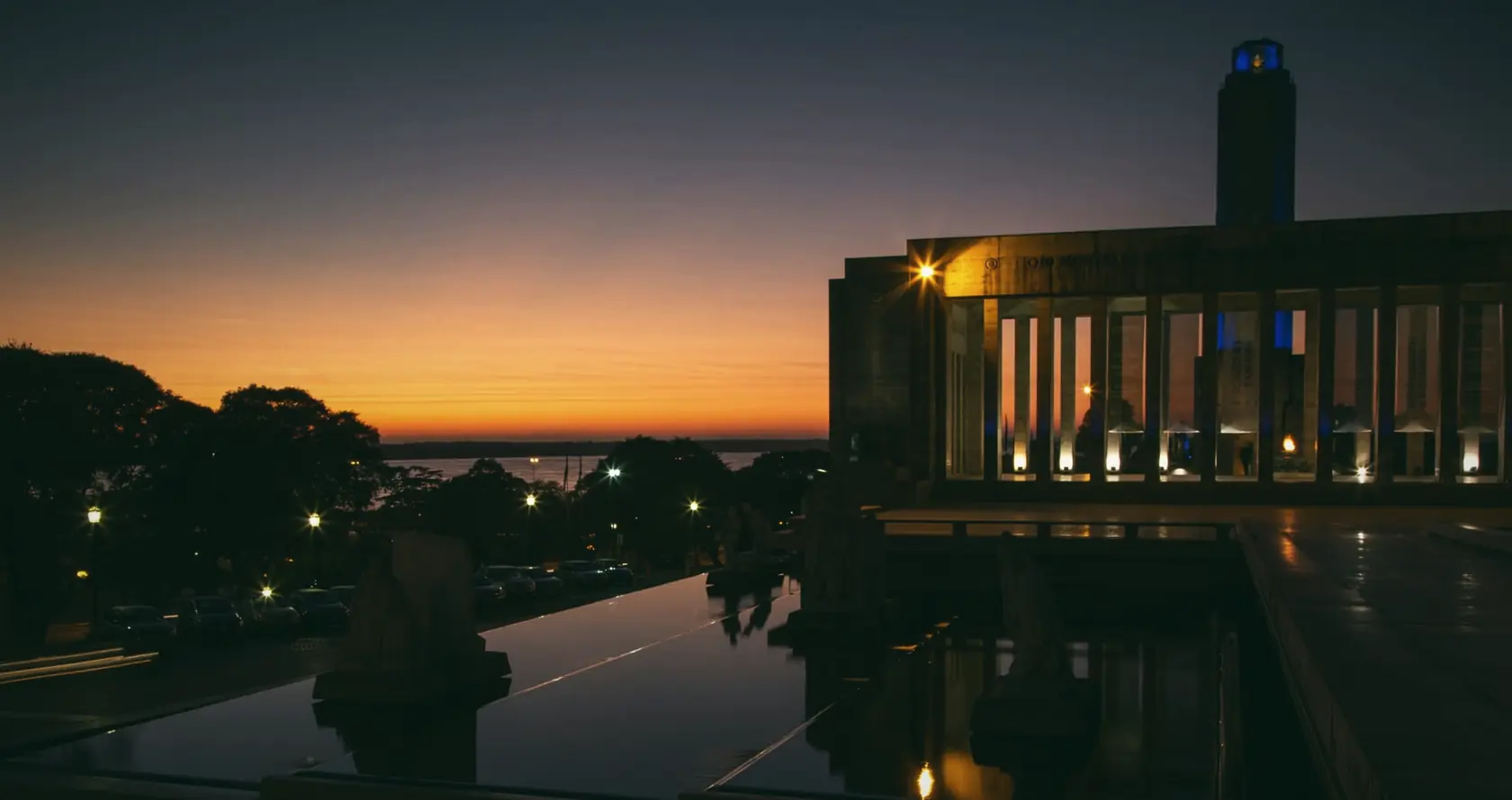 The Monumento a la Bandera, Rosario, at dawn, with its reflecting pool and an orange sky.